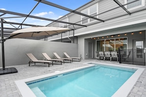 A swimming pool with lounge chairs and a covered seating area. - 5-bedroom townhome with a screened plunge pool at Solterra Resort, near Disney (Davenport)