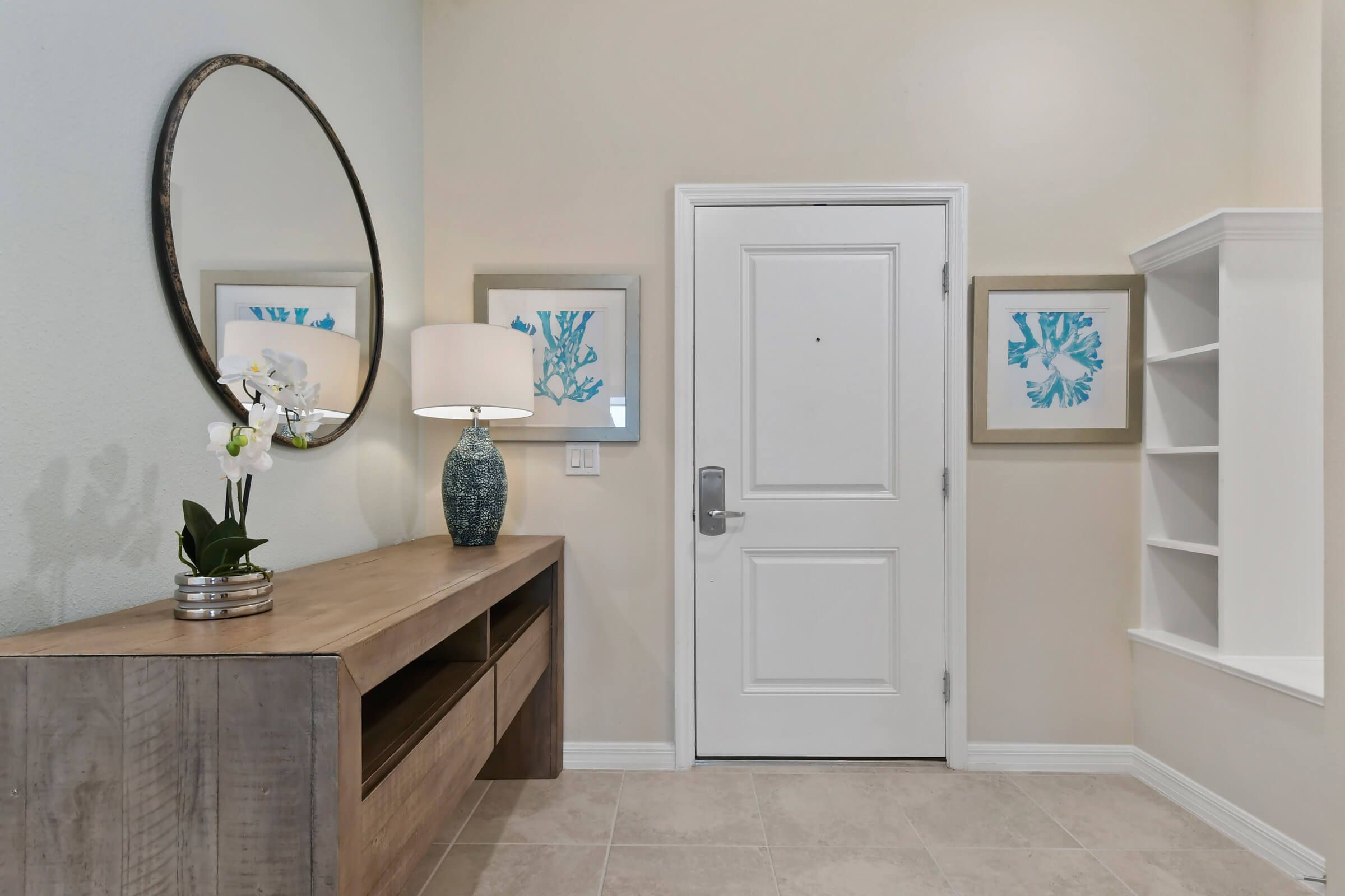 A hallway with a wooden bench, a door, and two framed artworks on the wall.