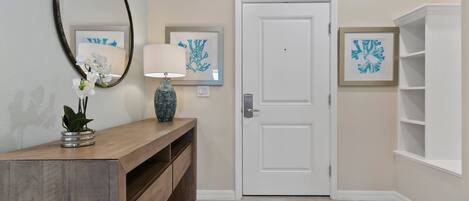 A hallway with a wooden bench, a door, and two framed artworks on the wall.