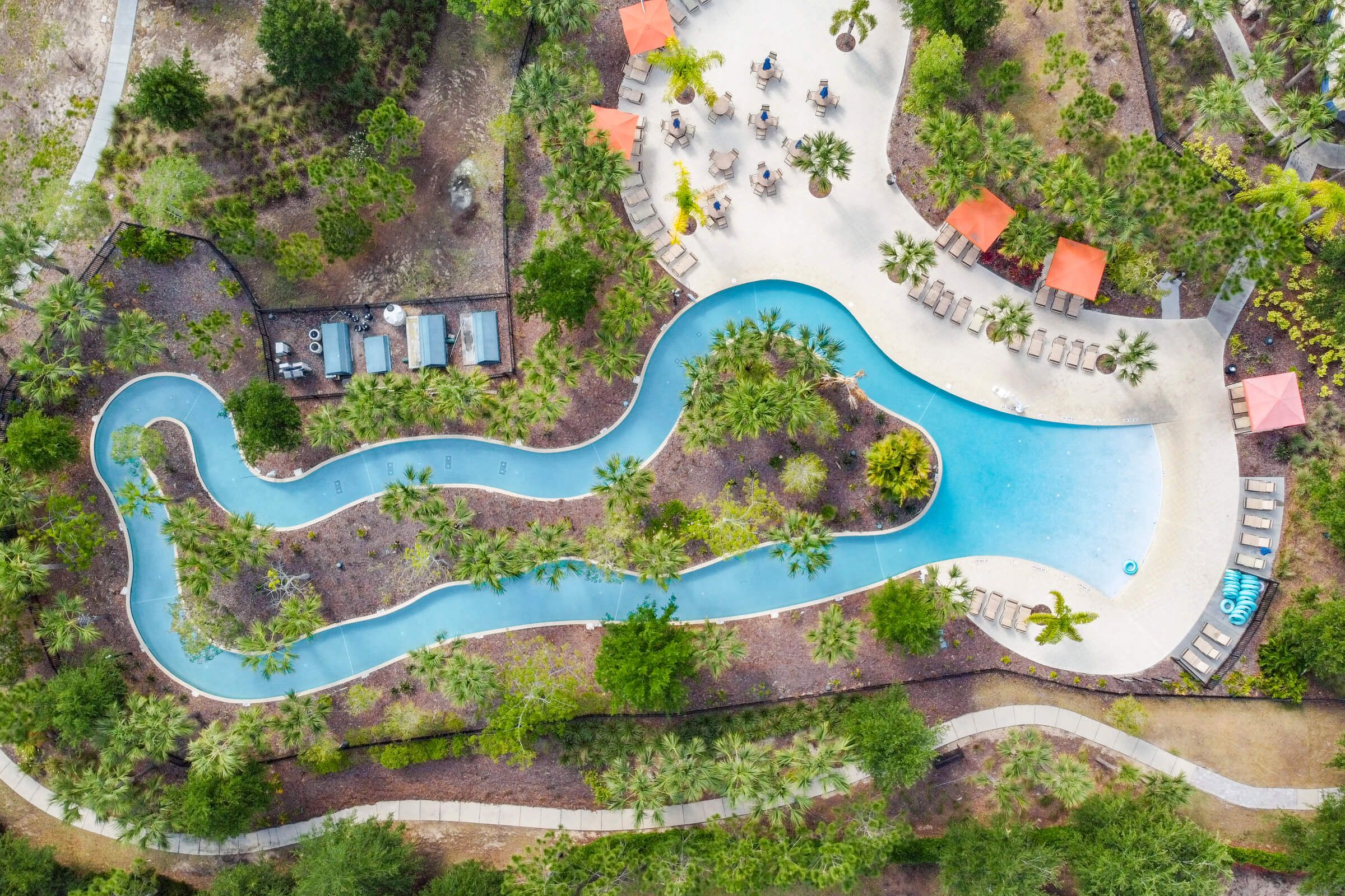Vista aérea de un resort con una piscina serpenteante, áreas de descanso y una variedad de vegetación.
