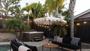 Un patio al aire libre con un sofá negro, una mesa redonda de centro y un jacuzzi.