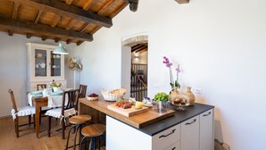 Une cuisine dotée d’un îlot central en bois, de meubles blancs et d’un coin repas avec des chaises et une table.