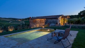 Une maison en pierre avec une piscine et un espace extérieur aménagé pour se détendre.