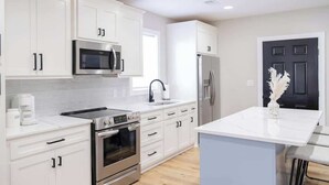 Una cocina moderna con armarios blancos, electrodomésticos de acero inoxidable y una puerta negra.