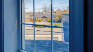 Vista a través de una ventana: cielo despejado, estacionamiento y edificios al fondo.