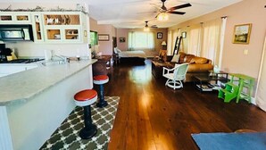 A spacious living area with a kitchen, a dining table, and a sofa. - Waterfront Splendor in the Woods. (Florence)