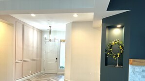 A hallway with a herringbone-patterned floor, a door with a light switch, and a wall-mounted light fixture. - Chimayo House with Pool and Spa near Palm Springs - Sleep 6 (Cathedral City)