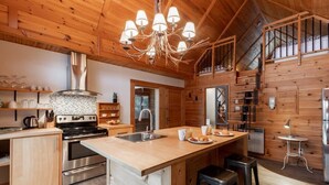 Una cocina moderna con paredes de madera, una isla central, electrodomésticos de acero inoxidable y una araña.