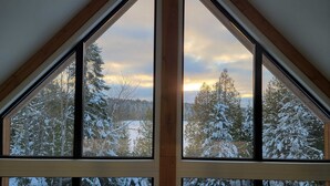 A room with large windows offering a view of a snowy forest landscape. - Nômade - Spa, private lake access & stunning views (Chertsey)