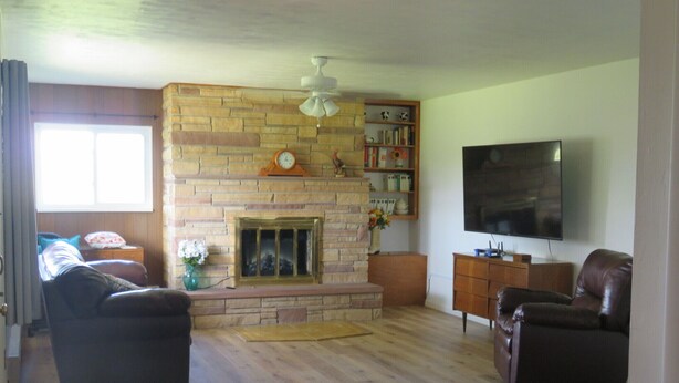 A living room with a stone fireplace, a television, and two leather sofas. - Charming 3-bedroom farmhouse with amazing views! (Durango)