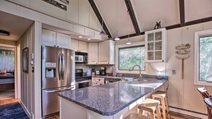 A modern kitchen with granite countertops, stainless steel appliances, and wooden stools. - COZY A-Frame Spacious Deck w/ Grill (Wintergreen)