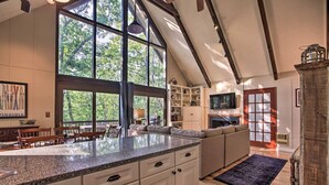 A spacious kitchen with a large island, wooden cabinets, and a view of the outdoors through large windows. - COZY A-Frame Spacious Deck w/ Grill (Wintergreen)