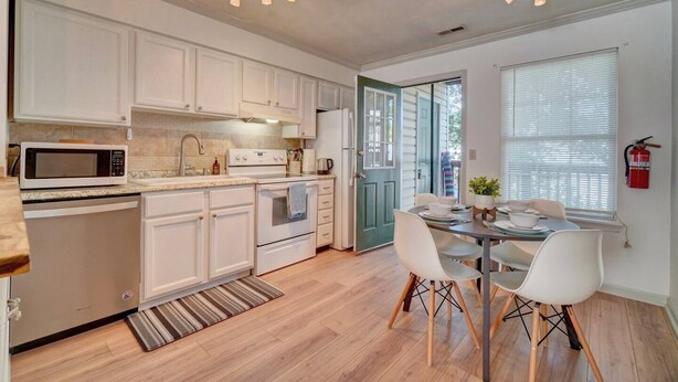A modern kitchen with white cabinets, a microwave, stove, and a dining area with a table and chairs. - King Bed WIFI - Work Space - 2 parking space B (Norfolk)