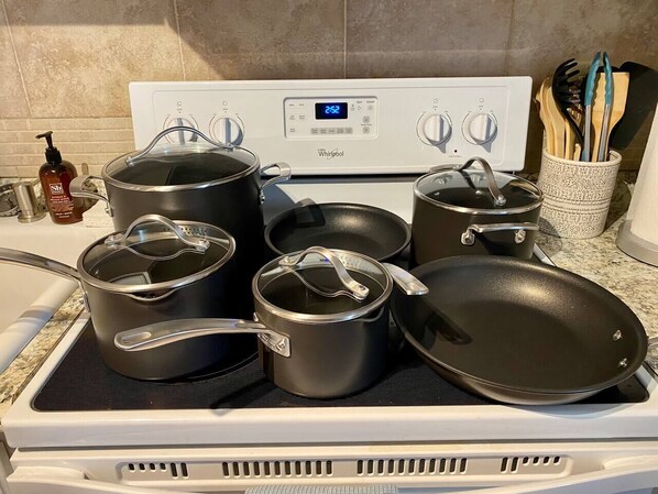 Une cuisine équipée d’une cuisinière Whirlpool, de différents ustensiles de cuisine et d’un étagère à épices.