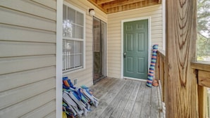 A covered porch with a wooden ceiling, a green door, and a row of colorful umbrellas. - King Bed WIFI - Work Space - 2 parking space B (Norfolk)