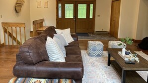 A spacious living room with a brown leather couch, a patterned rug, and a wooden coffee table.