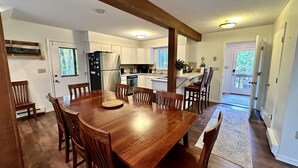A spacious kitchen with wooden cabinets, a central island, and a dining area with a large wooden table and chairs.