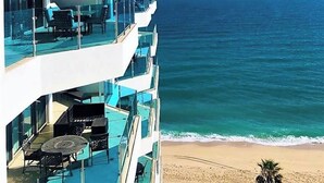 Ein mehrstöckiges Hotel mit Balkonen, das auf einen Strand und den Ozean blickt.