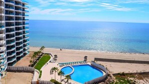 A hotel with a pool, beach, and ocean view.