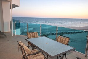 Ein Balkon mit Glasgeländer mit Blick auf einen Strand.