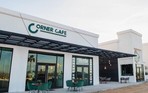 Ein Gebäude mit einem Schild, das "Corner Cafe" und "Thrifty" zeigt, und mit Außenplätzen.
