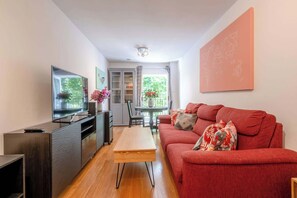 Un salon moderne avec un canapé rouge, une table basse en bois, un téléviseur et un coin repas comprenant une table et des chaises.