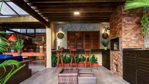 A cozy patio area with wicker furniture, a brick wall, and a tiled backsplash. - Carpediem - Incrível Casa Oásis no Ceará (Aquiraz)