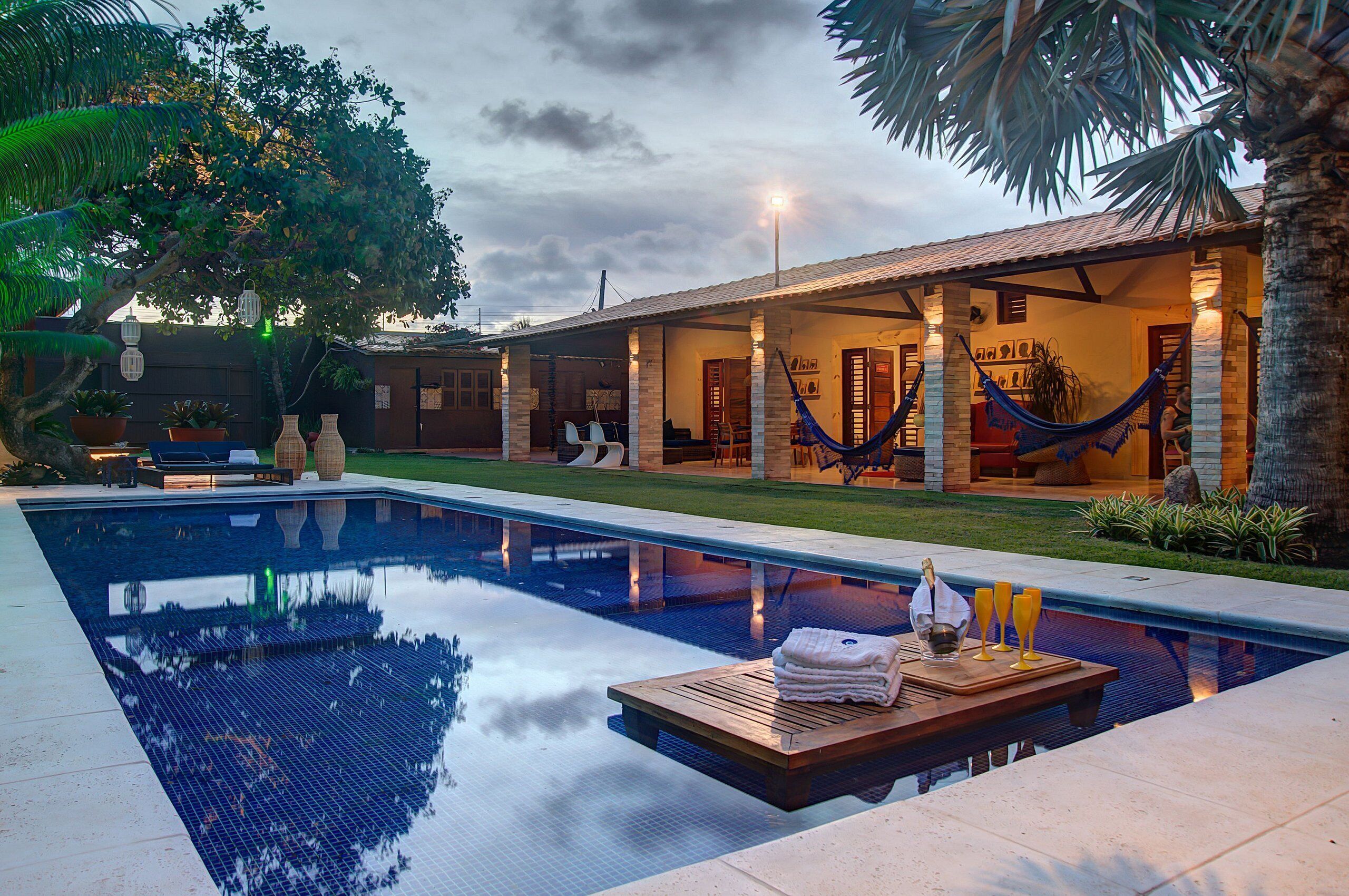 A poolside area with a clear pool, wooden deck, and a hammock.