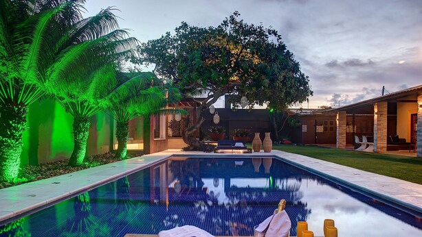 A swimming pool with a wooden deck, lounge chairs, and a tree in the background. - Carpediem - Incrível Casa Oásis no Ceará (Aquiraz)