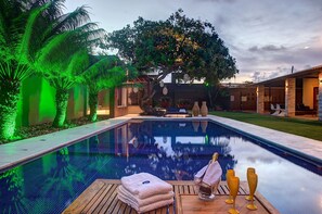 A swimming pool with a wooden deck, lounge chairs, and a tree in the background. - Carpediem - Incrível Casa Oásis no Ceará (Aquiraz)