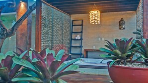 A modern spa area with a wooden deck, a large potted plant, a decorative Buddha statue, and a hanging light fixture. - Carpediem - Incrível Casa Oásis no Ceará (Aquiraz)