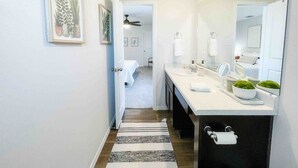 Un baño moderno con un lavamanos blanco, un espejo grande y una planta verde en la encimera.