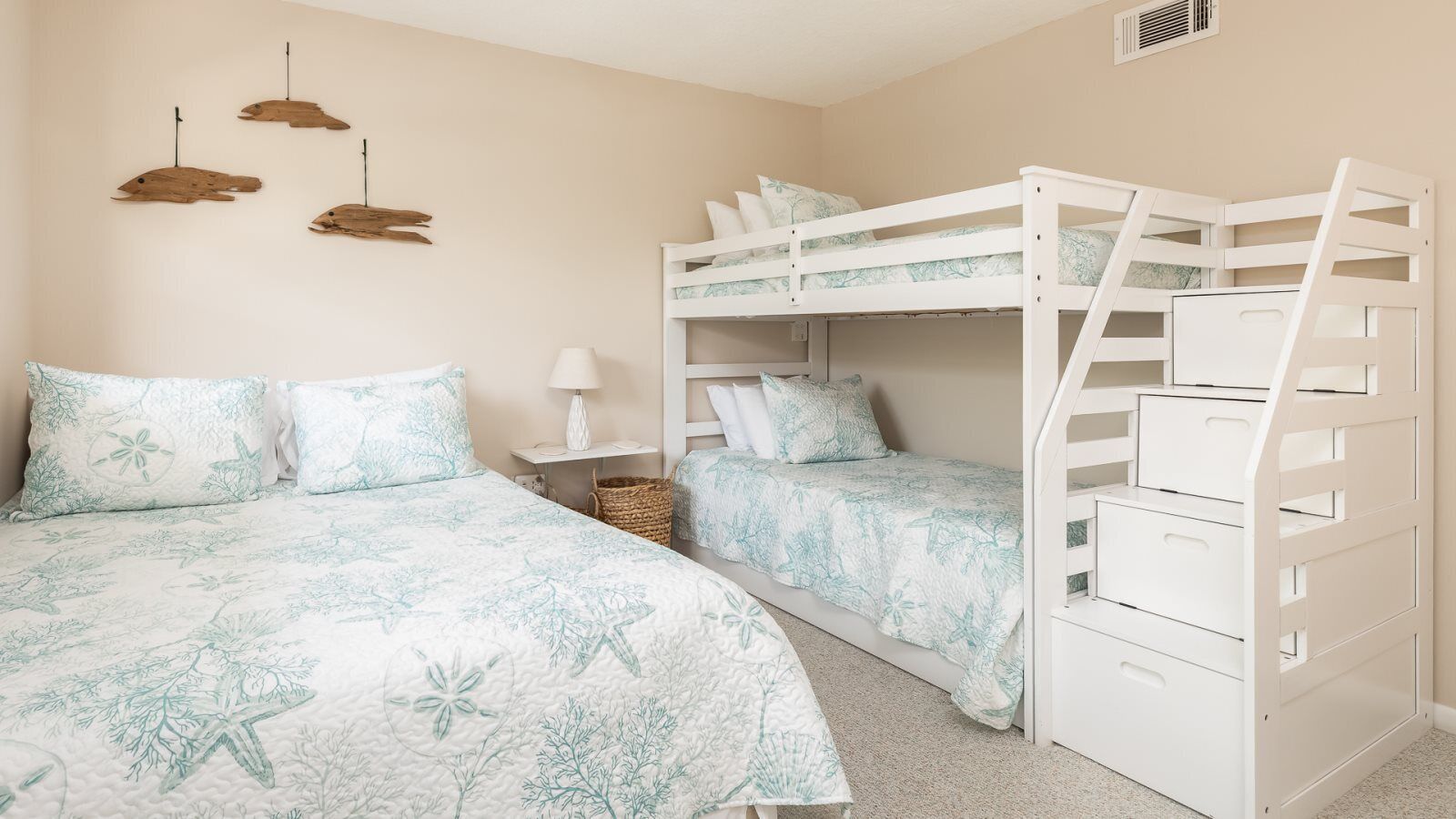 A bedroom with bunk beds, a bedside table with a lamp, and wall-mounted decor.