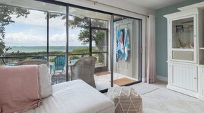 Un balcón con vista al mar, muebles de mimbre y un armario con banderas.