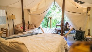 Acomodação em tenda com cama, cadeira, mesa e fogão.