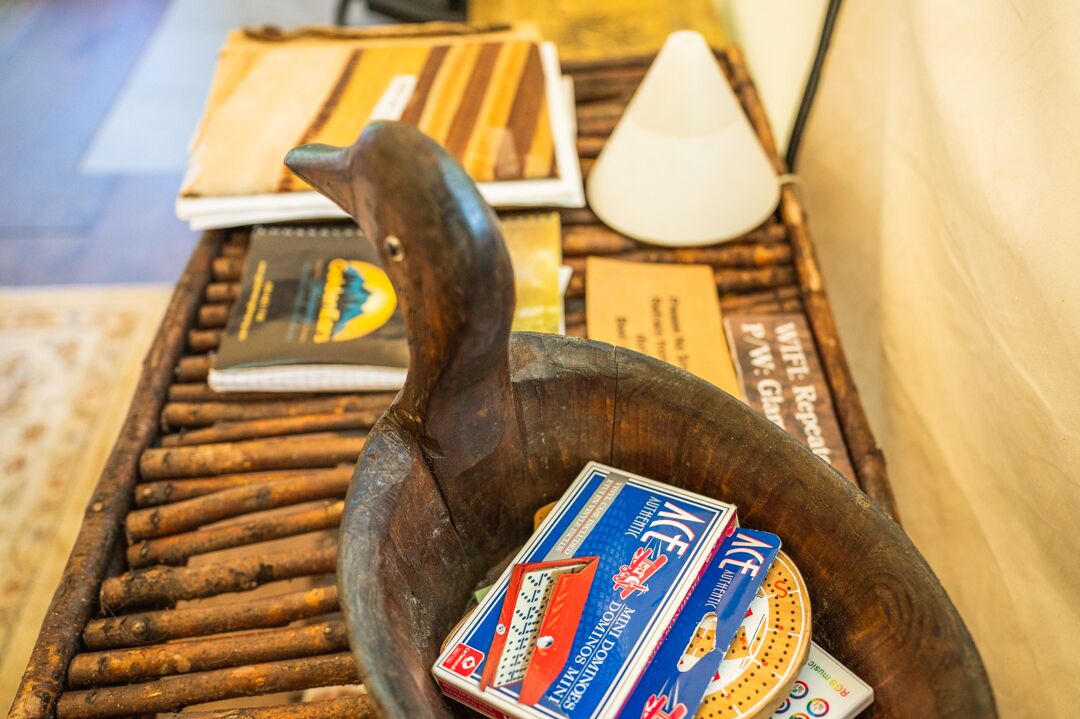 A wooden bowl with playing cards and a book on a table.
