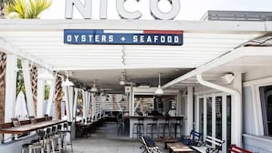A restaurant named 'NICO' with a sign indicating it serves oysters and seafood.