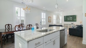 A spacious kitchen with a central island, white cabinetry, and a dining area with wooden chairs.