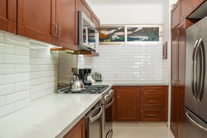 Una cocina funcional con azulejos blancos tipo metro, electrodomésticos de acero inoxidable y armarios de madera.