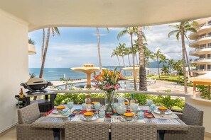 Comedor con vista al océano, mobiliario exterior y una parrilla.