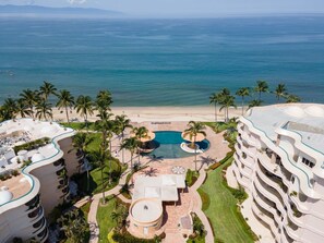 Un resort con piscina central, varios balcones y vista al mar.