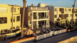 Un hôtel à plusieurs étages doté d’un balcon, d’un espace extérieur aménagé et de palmiers.