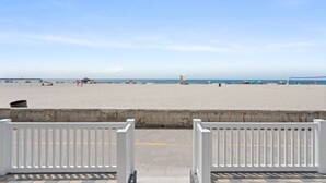 Blick auf einen Strand mit einem Betonweg und weißen Geländern.