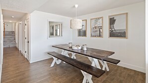 Ein Essbereich mit Holztisch und Bänken, gerahmten Bildern an der Wand und einer Treppe im Hintergrund.