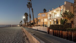 Ett hotell vid stranden med en balkong, palmer och en sandstrand.