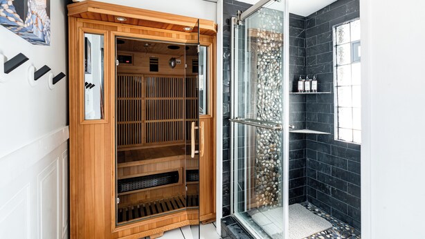 A modern bathroom with a glass shower enclosure, a wooden sauna, and a black tiled wall. - East Side Spa Retreat Near Lake, Restaurants and Fun (Milwaukee)