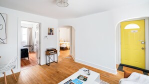 A modern living room with hardwood flooring, a white coffee table, and a yellow door. - East Side Spa Retreat Near Lake, Restaurants and Fun (Milwaukee)