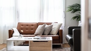 A living room with a brown leather sofa, a white coffee table, and a black leather armchair. - East Side Spa Retreat Near Lake, Restaurants and Fun (Milwaukee)