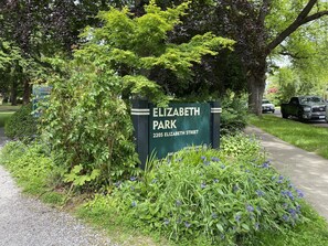 Un panneau indiquant l’entrée du parc Elizabeth, situé au 2205, rue Elizabeth, entouré de verdure et bordé d’un chemin de gravier.