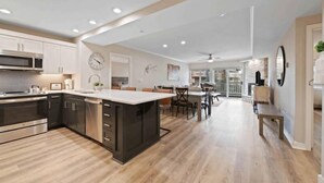 A modern kitchen with a central island, built-in appliances, and a dining area with a view. - Saint James Place 216 (Beaver Creek)